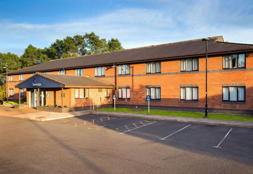 an exterior view of a days inn hotel with a brick facade and a parking lot in front at Travelodge Carlisle Todhills