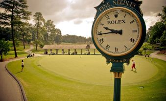a golf course with a rolex clock mounted on the side of the course , indicating that it is the golf ball in hand at Pine Needles Lodge & Golf Club