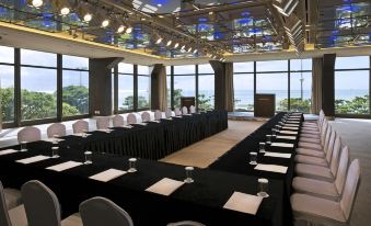 a large conference room with multiple long tables set up for a meeting , surrounded by windows overlooking the ocean at Paradise Hotel Busan