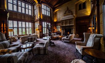 a large , elegant living room with multiple couches and chairs arranged around a fireplace , creating a cozy atmosphere at Bovey Castle