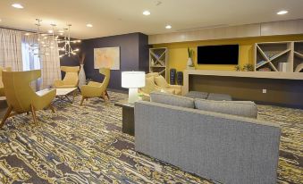 a modern living room with a gray couch , yellow chairs , and a television on the wall at Eastwood Hall