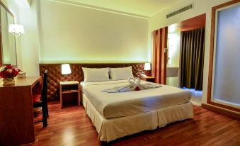 a large bed with a wooden headboard and footboard is in a room with hardwood floors at Viva Hotel Songkhla