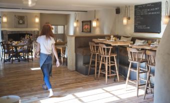 a woman is walking through a restaurant with wooden floors and chairs around tables at The White Hart
