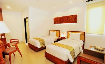 a hotel room with two beds , a nightstand between them , and a wooden headboard on the wall at Kautaman Hotel
