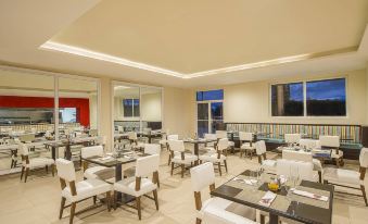 a large dining room with white chairs and tables , along with a balcony overlooking the ocean at Four Points by Sheraton Puntacana Village