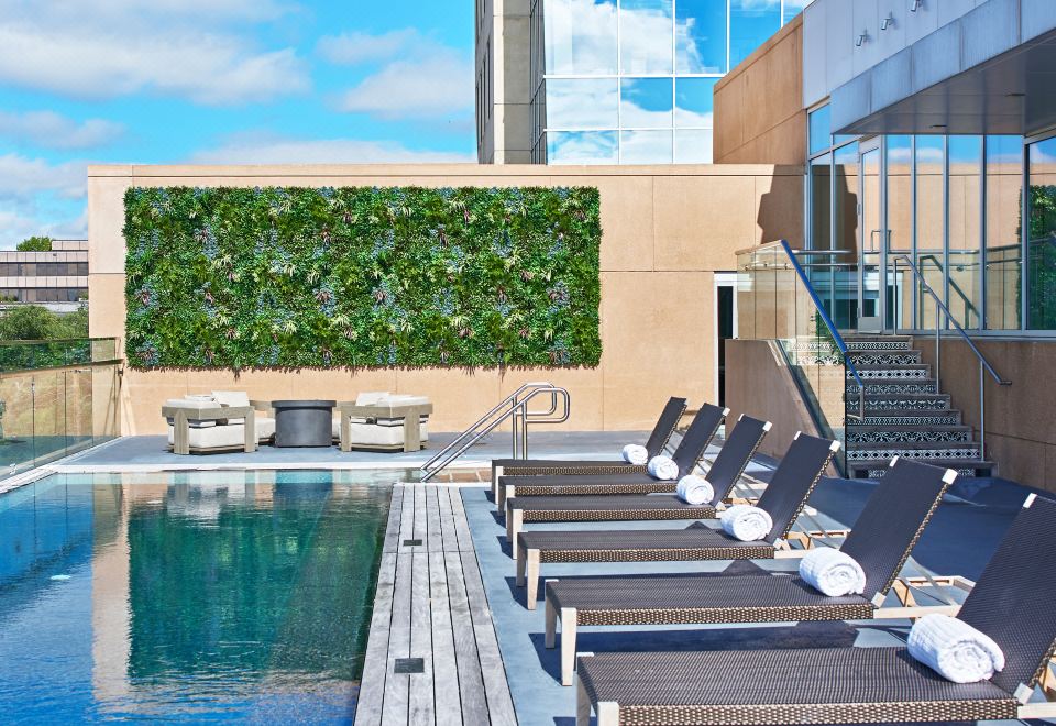 a poolside lounge area with lounge chairs , a green wall , and a staircase leading to an outdoor pool at The Fontaine
