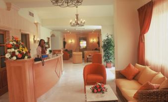 a hotel lobby with an orange reception desk , two chairs , and a chandelier hanging from the ceiling at Sunflower Hotel