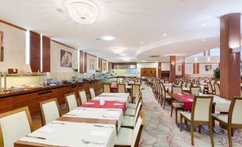 a large dining room with numerous tables and chairs arranged for a group of people to enjoy a meal together at Hotel Boss