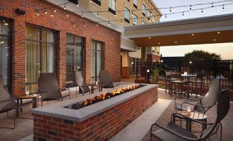 a brick outdoor patio with a fire pit surrounded by chairs and tables , creating a cozy atmosphere at Courtyard LaGrange