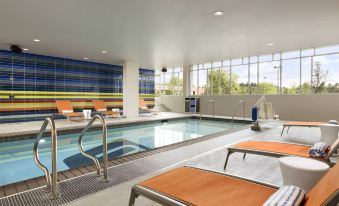 an indoor swimming pool surrounded by chairs and tables , providing a relaxing atmosphere for guests at Aloft Hillsboro-Beaverton