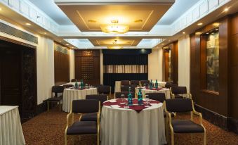 a dining room with round tables covered in white tablecloths and chairs arranged around them at Park Inn by Radisson New Delhi Lajpat Nagar