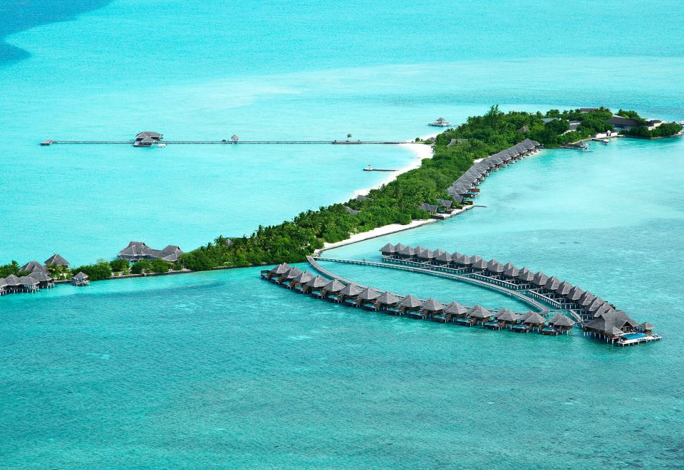 a picturesque tropical island with multiple water villas and a long strip of stone walkways leading to a calm blue ocean at Taj Exotica Resort & Spa