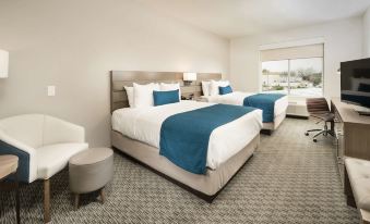 a modern hotel room with two beds , each made up with blue and white linens , flanked by nightstands and lamps at Best Western Plus Executive Residency Austin