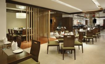 a modern restaurant with wooden tables and chairs , a bar area , and a dining room at Four Points by Sheraton Ahmedabad