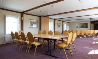 a large conference room with wooden tables and chairs arranged in a semicircle , providing seating for a group of people at The Mill Hotel