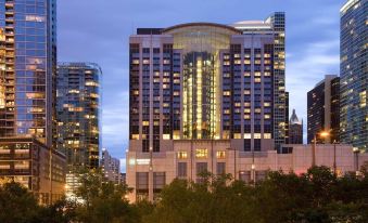 a tall building with many windows and a tall tower , surrounded by trees and lit up at night at Embassy Suites by Hilton Chicago Downtown Magnificent Mile
