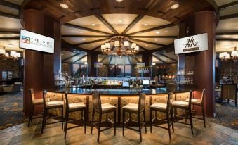 a modern bar with a wooden ceiling , multiple tables and chairs , and a large chandelier at Lodge of Four Seasons Golf Resort, Marina & Spa