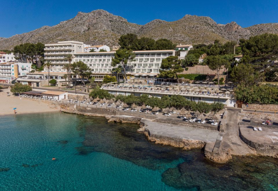 a resort with a large hotel situated on the beach , surrounded by mountains and clear blue water at Grupotel Molins