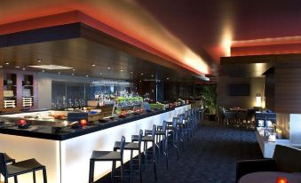 a modern restaurant with a long bar , several stools , and a variety of food and drinks at The Westin Chicago North Shore