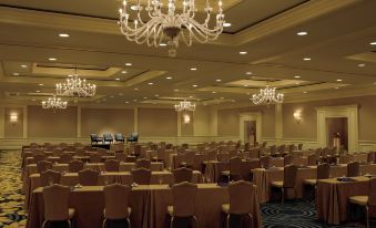 a large conference room with many tables and chairs , a chandelier hanging from the ceiling , and other tables at The Ritz-Carlton, Marina del Rey