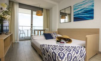 a bedroom with a large bed , a painting on the wall , and a door leading to a balcony at Pierre & Vacances Blanes Playa