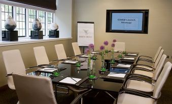 a conference room with a long table set for a meeting , surrounded by chairs and a podium at Bovey Castle