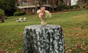 a table with a gray and black tablecloth is set up in a grassy area , surrounded by trees at Black Swan Inn