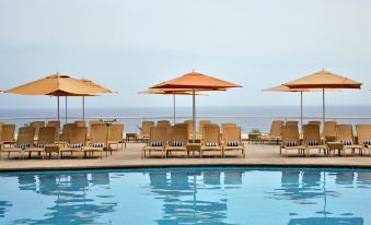 a beautiful outdoor pool area with umbrellas , lounge chairs , and a view of the ocean at Venezuela Marriott Hotel Playa Grande