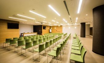 a large conference room with rows of green chairs arranged in a semicircle , and a podium at the front of the room at Quality Hotel San Martino