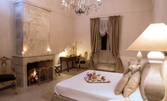 a luxurious bedroom with a large bed , white linens , and a tray of food on the bedside table at Castello Camemi