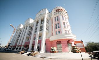 a large pink and white building with columns , possibly a hotel or a restaurant , situated on a city street at Hotel Europe