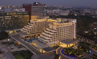 a large hotel surrounded by a city , with many people gathered around it to relax and enjoy the view at Sheraton Grand Bengaluru Whitefield Hotel & Convention Center