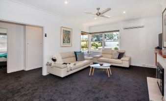 a spacious living room with a couch , chairs , and a coffee table in front of a window at Lake Wendouree Luxury Apartments