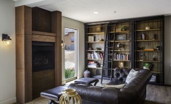 a cozy living room with a brown leather couch , a fireplace , and a bookcase filled with books at Red Sands Hotel