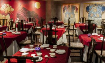 The restaurant is adorned with red tablecloths and white chairs, complemented by pictures on the wall at Caesar Park Hotel Taipei