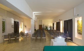 a large , empty conference room with rows of chairs and a podium in the center at Hotel Tirreno
