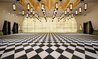 a large , open room with a black and white checkered floor and a row of hanging lights at Kempinski Hotel Ishtar Dead Sea