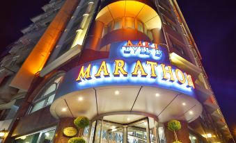 "the entrance of a building with the sign "" marathon "" in multiple languages , illuminated at night" at New Marathon Hotel