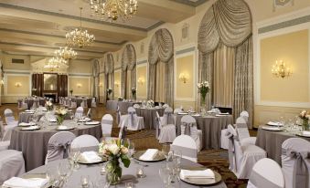 a large , elegant banquet hall with multiple tables set for a formal event , each table having its own unique arrangement of flowers at Francis Marion Hotel