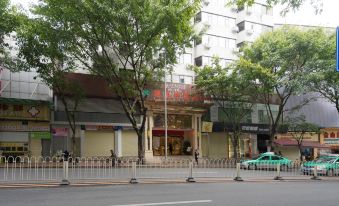 A street with pedestrians, an empty building, and parked cars at Vienna Hotel (Guangzhou railway station & Xiaobei subway station)