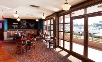 a large , open room with wooden floors and windows that let in natural light , possibly from a restaurant or bar at Wilsonton Hotel