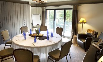 a conference room with a round table surrounded by chairs , and a tv mounted on the wall at Hotel-Musee Premieres Nations