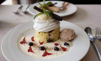 a white plate with a delicious dessert on it , topped with whipped cream and blueberries at Zig ZAG Motel & Apartments
