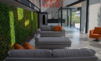a modern living room with gray couches , orange pillows , and a green wall art at Hangar Inn Guadalajara Aeropuerto