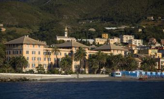 a beautiful coastal town with palm trees , buildings , and a church , situated near the water at Grand Hotel Arenzano