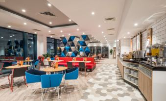 a modern restaurant with colorful seating and a checkered floor , featuring a dining area with tables and chairs at Holiday Inn Express Stockport