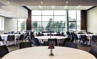 a large dining room with round tables and chairs arranged for a group of people at Mercure Sydney Liverpool