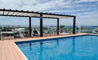 a rooftop pool with a view of the city , surrounded by lounge chairs and umbrellas at Four Points by Sheraton Veracruz