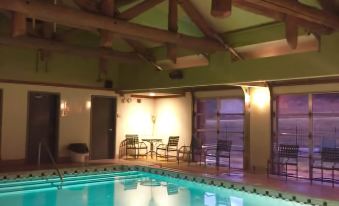 an indoor swimming pool surrounded by chairs and tables , with a view of the outside at Quartz Mountain Resort