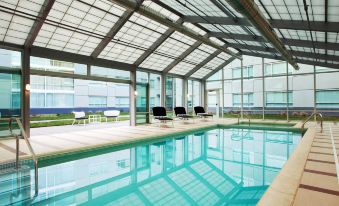 a modern swimming pool with a glass roof , surrounded by lounge chairs and buildings , under a clear blue sky at Sheraton Valley Forge King of Prussia